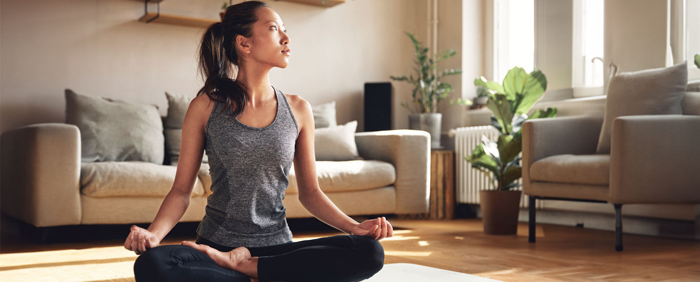 Vrouw in yogahouding op de mat in de woonkamer. 
